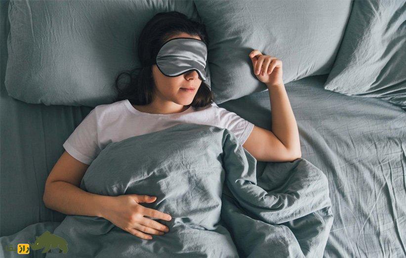 چرا انسان خواب میبیند و چه کسانی بیشتر خواب میبینند؟ زنی در حال خوابیدن با چشم بند خواب